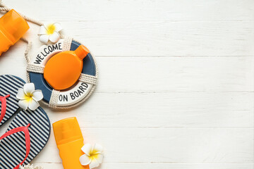Composition with flip-flops, decorative lifebuoy ring, plumeria flowers and bottles of sunscreen...