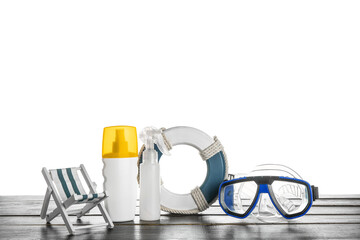 Swimming mask, bottles of sunscreen cream, decorative deckchair and lifebuoy ring on wooden table...