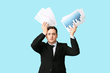 Worried young businessman with diagrams and graphics on blue background