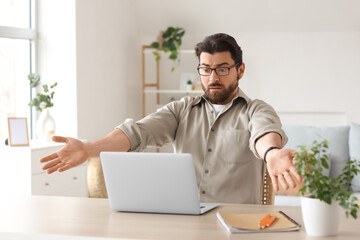 Upset fired young man with laptop on table at home