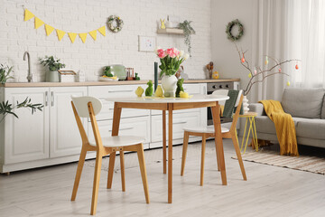 Interior of festive kitchen with sofa, tulip flowers, rabbits and baby chickens on dining table