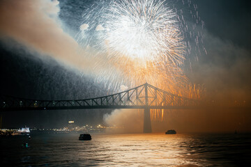 Drone flight through holiday fireworks above water with reflection on the black sky background