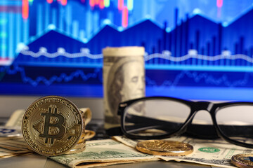 Bitcoins and dollar banknotes on laptop with exchange rates diagrams, closeup