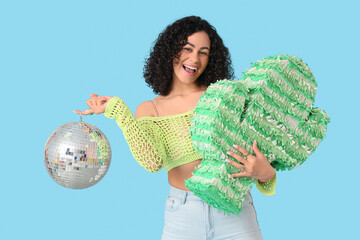 Happy woman with disco ball and pinata on blue background