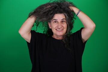 Woman with a variety of emotions, wearing a black t-shirt ,standing against a green background....