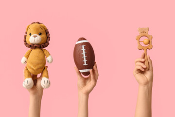 Hands holding baby toys on pink background