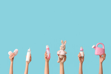 Hands holding baby accessories on blue background