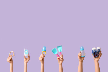 Hands holding baby accessories on lilac background