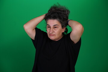 Woman with a variety of emotions, wearing a black t-shirt ,standing against a green background....