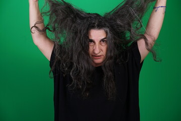 Woman with a variety of emotions, wearing a black t-shirt ,standing against a green background....
