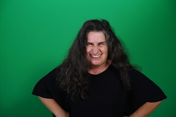 Woman with a variety of emotions, wearing a black t-shirt ,standing against a green background....