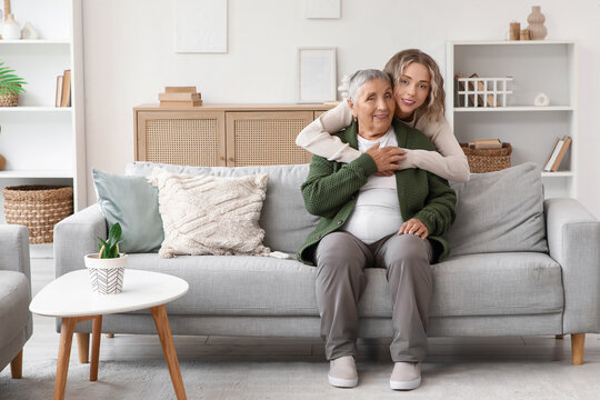 Young woman hugging her grandmother on sofa at home