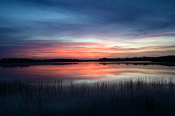 Colorful sunrise cloudscape reflected in calm water of Nine Mile Pond in Everglades National Park, Florida.