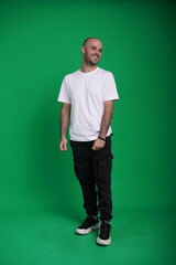 Fototapeta premium Young man with a variety of emotions, wearing a white t-shirt standing against a green background. Studio shot with copy space.