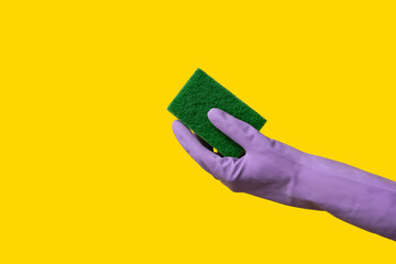 Hand in rubber glove holding sponge for cleaning on yellow background