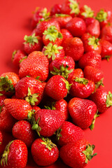 Many sweet ripe strawberries on red background