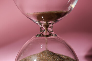 Crystal hourglass on pink background, closeup
