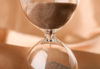 Crystal hourglass on beige background, closeup