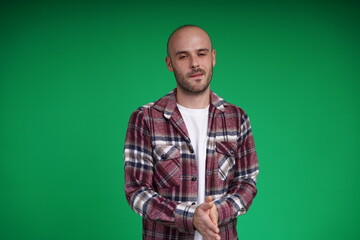 Fototapeta premium Young man with a variety of emotions, wearing a white t-shirt standing against a green background. Studio shot with copy space.