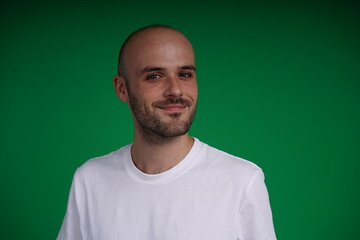 Young man with a variety of emotions, wearing a white t-shirt standing against a green background. Studio shot with copy space.