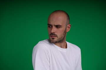 Obraz premium young man wearing a white t-shirt standing against a green background. Studio shot with copy space.