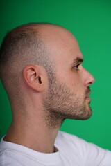 Obraz premium young man wearing a white t-shirt standing against a green background. Studio shot with copy space.