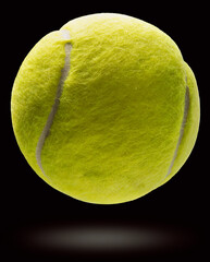 Yellow Tennis ball floating in the air isolated on a black background, Yellow Tennis ball on black Background With clipping path.