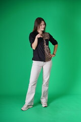 A young woman poses in a studio with a green background, showing natural emotions, full of expressions and dynamic movements. Unedited image