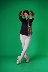 A young woman poses in a studio with a green background, showing natural emotions, full of expressions and dynamic movements. Unedited image