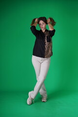A young woman poses in a studio with a green background, showing natural emotions, full of expressions and dynamic movements. Unedited image