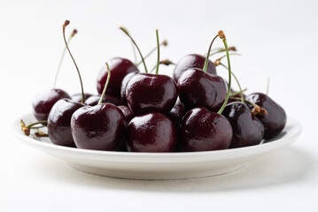 Fresh ripe cherries fruit on white plate with clean white background, Healthy eating and seasonal