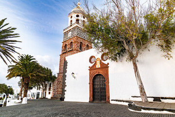 The bell tower of Nuestra Señora de Guadalupe Church rises above the rooftops of the street market...