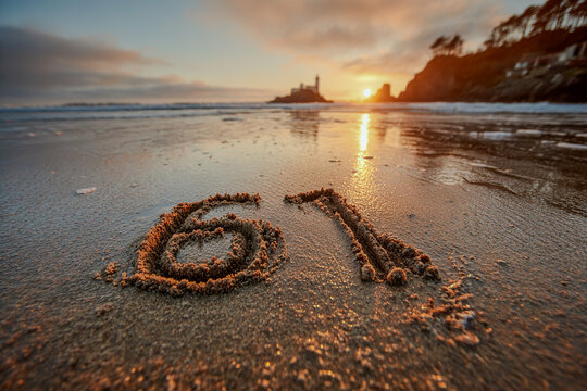Number 61 Written in Soft Golden Sand with Peach Hues and Pastel Sky Above a Tranquil Coastal Landscape
