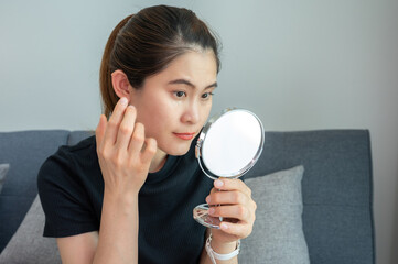 Asian woman applying anti aging cream on her under eyes. The anti aging cream is using to reducing, masking or preventing signs of skin aging.