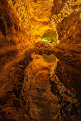 Inside Cueva de los Verdes, Lanzarote, where tourists explore an ancient volcanic tunnel. Dramatic rock formations, dim lighting, and echoing sounds