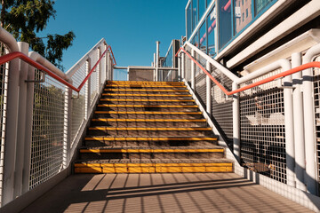 Empty staircase leading to train station platform on sunny day