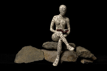 Small figurines covered in letters reading books