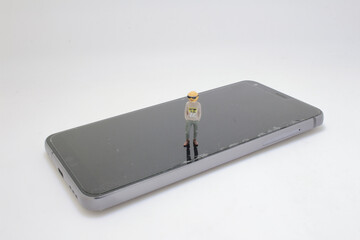 Miniature Figure Standing on Smartphone Highlighting Technology Perspective