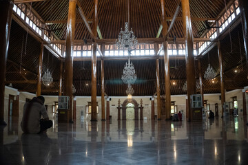 Interior view of Masjid Agung Surakarta, showcasing grand chandeliers, traditional wooden pillars, and serene architecture.