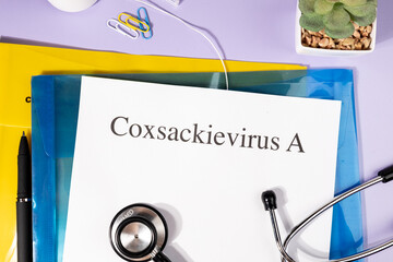 A Paper with “Coxsackievirus A” Title in Clipboard Set on the Desk with Stethoscope – Hand,...
