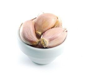 Garlic cloves cut into pieces, placed in a white bowl on a white background.