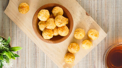 Top view of dried choux pastry filled with sweet cheese cream in a bowl with a cup of tea isolated...
