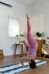 Elder woman exercising yoga in a head stand Sirsasana pose of placing