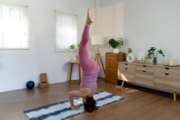 Elder woman exercising yoga in a head stand Sirsasana pose of placing