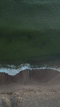 Vertical Sideways Drone Flight Along Shoreline with Waves Crashing on Sand &ndash; 9:16 Aerial Footage
