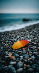 Colorful umbrella on a pebbled beach, ocean in background