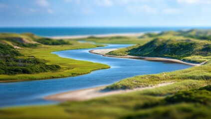 Serpentine river meanders through coastal dunes, meeting a calm ocean under a bright sky