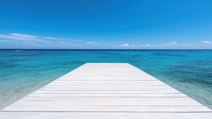 Fototapeta premium Long pier extends into clear blue sea under bright sky, creating serene atmosphere