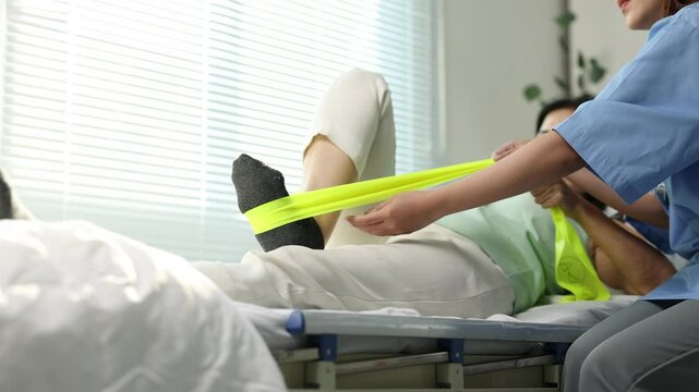 Doctor assisting patient with leg exercises using resistance band.