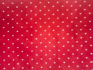 The texture of the red carpet with a white dot motif neatly arranged in a straight line gives an elegant impression as a background for industrial product catalog design.